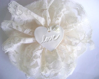 May include: White lace doily with a white ceramic heart that says "love" on it.