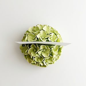 Puede incluir: Un arreglo floral de hortensias verdes con una tarjeta en blanco para un porta nombres.