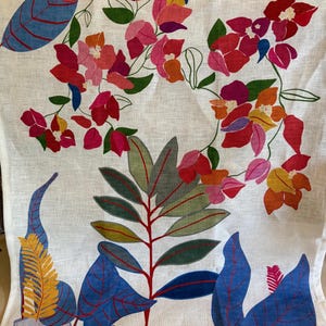May include: White fabric with a colorful floral design. The design features red, pink, orange, and yellow flowers with green leaves and blue foliage. The fabric has a linen-like texture.