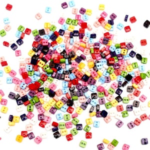 May include: A large assortment of colorful plastic buttons with two holes each. The buttons are in various shades of red, blue, green, yellow, pink, purple, white, and black.