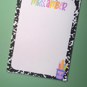 May include: A rectangular notepad with a black and white cow print border. The top features the text A Note From Mrs. Amber in colorful letters. The bottom right corner displays a purple pencil holder with pencils and a ruler and the text Made To Teach.