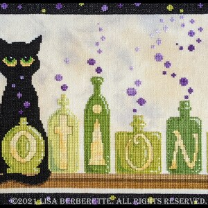 May include: Cross-stitch design featuring a black cat with green eyes sitting in front of green potion bottles. The word "POTIONS" is spelled out in large letters. Purple bubbles float above the bottles. The design is framed in black.