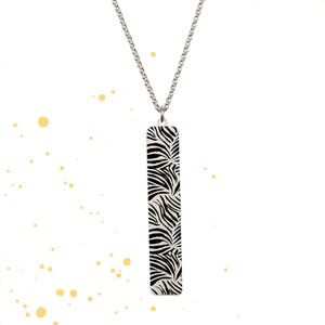 May include: A silver chain necklace with a rectangular pendant featuring a black and white zebra print design.