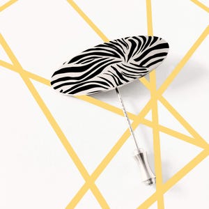 Könnte beinhalten: Eine silberne Nadel mit einem ovalen Kopf in Schwarz-Weiß-Zebra-Muster.