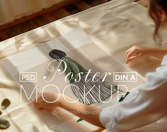 Könnte beinhalten: Ein Poster-Mockup mit einer Frau, die ein Poster mit einer Schwarzweißillustration einer Person in einem grünen Kleid hält. Das Poster ist mit "Poster Mockup" und "DIN A" beschriftet.