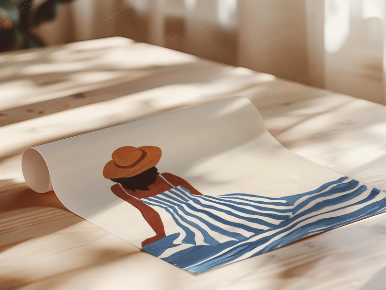 May include: Rolled art print featuring a woman in a blue and white striped dress and a brown hat. The illustration depicts a person relaxing in a sunny setting. The artwork is displayed on a wooden surface.