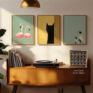 May include: Three framed art prints with gold frames. The prints feature a pair of pink flamingos, a black cat, and a Dalmatian dog with a puppy. A record player and vinyl records sit on a wooden cabinet. A Beatles album cover is visible.
