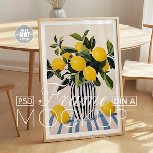 Puede incluir: Una impresión enmarcada de un bodegón con un ramo de limones en un jarrón de rayas azules y blancas. Los limones están dispuestos en un racimo, con algunos limones que se caen del jarrón. El fondo es de color beige claro.