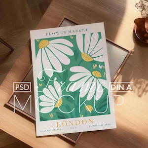 以下が含まれることがあります： 緑色の背景に白いデイジーが描かれた、花柄の額装されたプリント。プリントの上部には「FLOWER MARKET」、下部には「BY LONDON GALLERY PRINTS NO. 2 BOTANICAL SERIES」というテキストが書かれています。