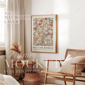 May include: A framed art print featuring a colorful floral design with the text "WILLIAM MORRIS". The print is in a wooden frame and hangs on a white wall. The room includes a wooden chair, a small table, and a woven basket.