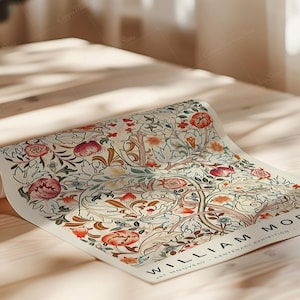 May include: Rolled poster featuring a floral design with red, orange, and blue flowers, and green leaves. The poster has the text "WILLIAM MORRIS" and "ART NOUVEAU - CENTENARY EXHIBITION - MOTIF CLASSIQUE". The poster is on a wooden surface.