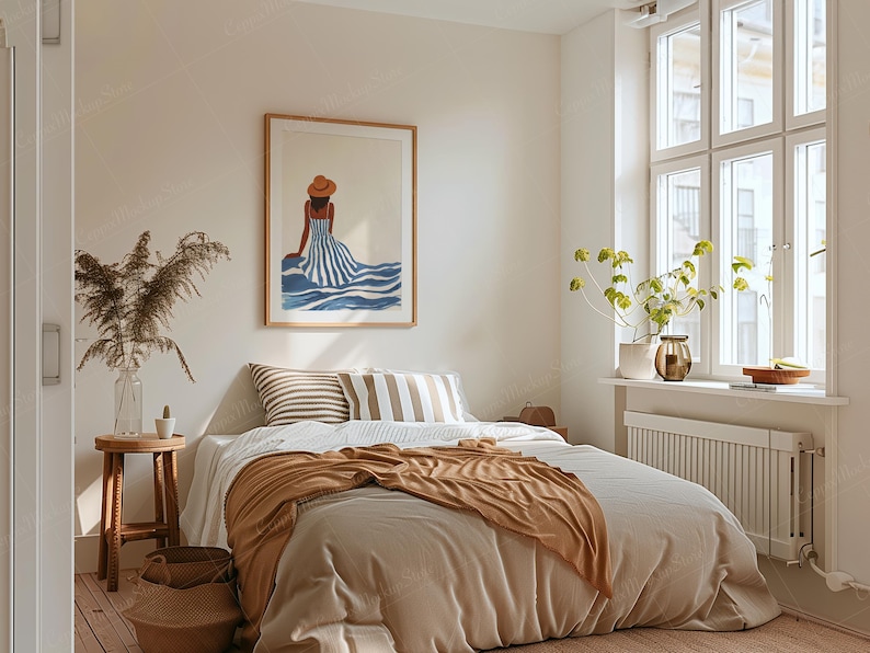 May include: A bedroom scene with a large framed artwork depicting a woman in a striped dress and hat. The bed is made with neutral-toned bedding and a brown throw blanket. A small wooden stool and a vase with dried plants are also visible.