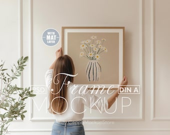 Maqueta de marco cuadrado con persona, mano realista de 1x1, póster minimalista grande, mujer colgando en la pared de madera fina, plantilla PSD para Photoshop Home