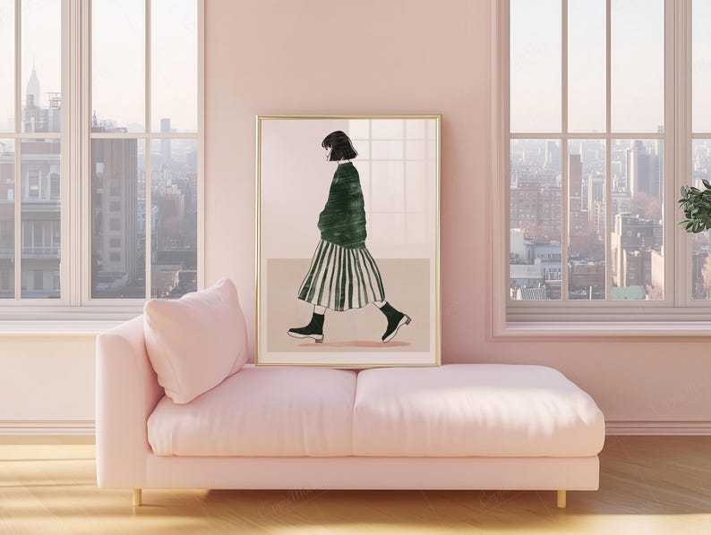 May include: A framed art print featuring a figure in a green sweater and striped skirt, walking. The artwork is displayed on a wall above a pink chaise lounge. The room has large windows with a city view.