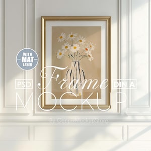 以下が含まれることがあります： デイジーの花瓶が描かれた額入りのアートプリント。アートワークは、白いマットが付いた金色のフレームに入っています。背景はニュートラルなベージュ色です。「Frame Mockup」というテキストが画像に表示されています。