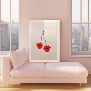 May include: A framed art print featuring a pair of red lips with green stems, resembling cherries. The artwork is displayed on a light pink wall above a matching chaise lounge. Large windows offer a view of a cityscape.
