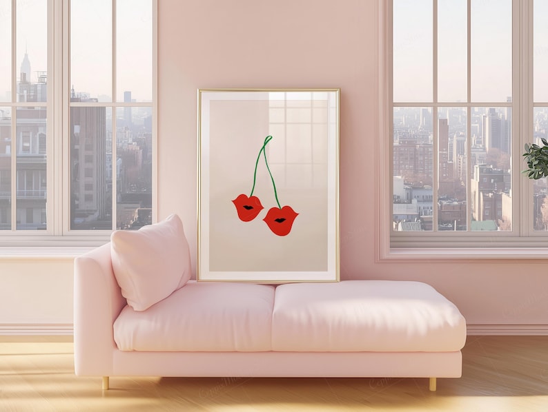 May include: A framed art print featuring a pair of red lips with green stems, resembling cherries. The artwork is displayed on a light pink wall above a matching chaise lounge. Large windows offer a view of a cityscape.