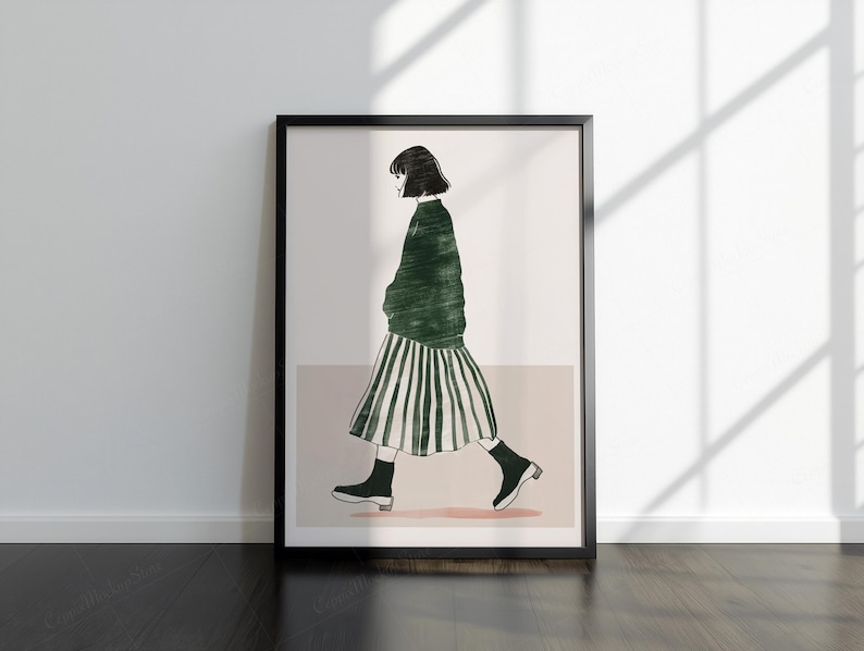 May include: A framed art print showing a minimalist illustration of a person walking. The figure is wearing a green sweater and a striped skirt, with black shoes. The artwork is set against a neutral background.