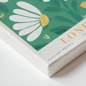 May include: A canvas print with a floral pattern of white daisy-like flowers and green leaves on a teal backdrop. The print includes the text "LONDON NO. 3 GALLERY PRINTS" in gold lettering.