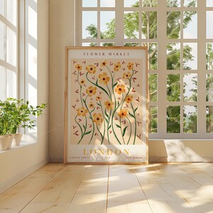 May include: A framed poster with a floral design featuring yellow flowers and green stems on a light pink background. The poster has the text "FLOWER MARKET LONDON" at the top and bottom.