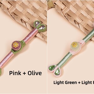 Op de afbeelding: Twee decoratieve Hanbok-knoppen, &eacute;&eacute;n roze en olijf, de andere lichtgroen en lichtroze. Elke knop heeft een centrale bloemversiering en hartvormige kristallen accenten. De tekst "Pink + Olive" en "Light Green + Light Pink" is zichtbaar.