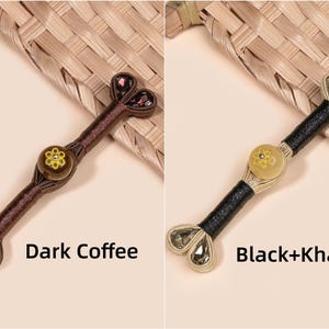 Op de afbeelding: Twee decoratieve haarstokjes, &eacute;&eacute;n donker koffie en de andere zwart en kaki. Elk stokje heeft een centraal bloemmotief en hartvormige accenten aan de uiteinden. De tekst "Dark Coffee" en "Black+Khaki" staat eronder.