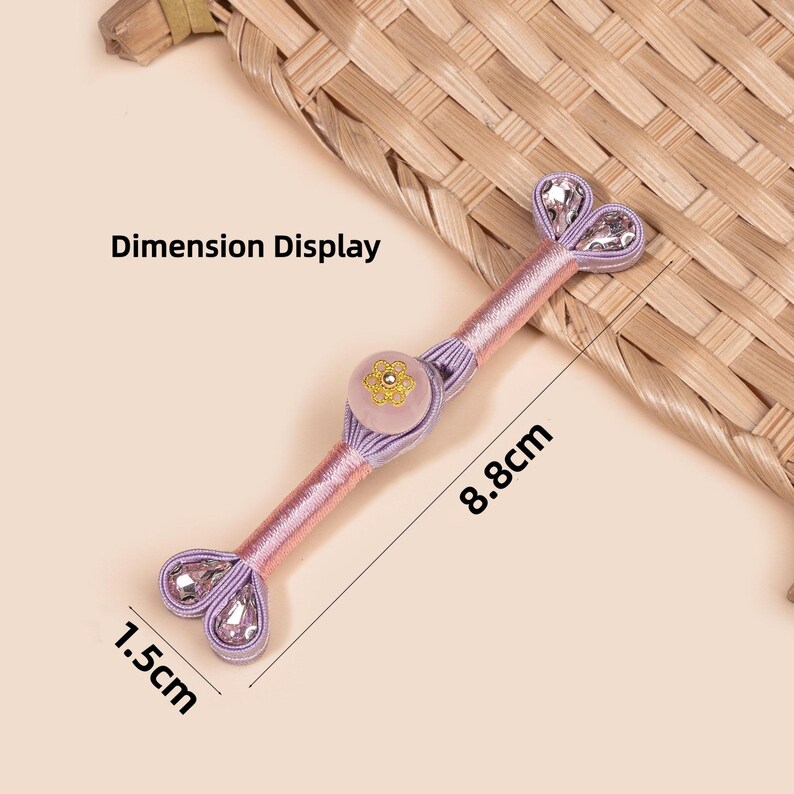 Op de afbeelding: Decoratieve roze en lavendelkleurige knoop met een bloemmotief en heldere kristallen accenten. De knoop is 8,8 cm lang en 1,5 cm breed. De tekst "Dimension Display" is zichtbaar.