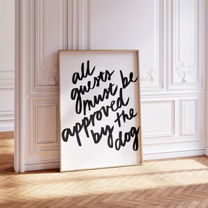 May include: A black and white framed print with the text "all guests must be approved by the dog" in a handwritten style.