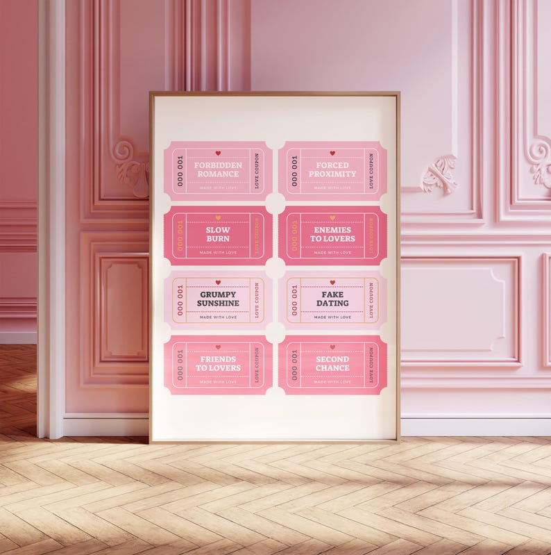 May include: A framed print featuring eight pink love coupons with phrases like "Forbidden Romance" and "Fake Dating." The coupons have a vintage ticket design with a heart and the words "Made with Love." The print is displayed against a pink wall.