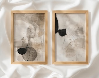 Puede incluir: Dos cuadros rectangulares con marcos de madera clara. Cada lámina presenta composiciones abstractas con círculos de tinta negra, líneas oscuras finas y lavados de acuarela en tonos beige y gris sobre un fondo claro, creando un diseño equilibrado.