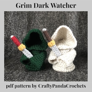 Può includere: Schema all'uncinetto per un Grim Dark Watcher, con due figure in vesti con cappuccio, una verde e una bianca, ciascuna con un coltello d'argento. Lo schema è di CraftyPandaCrochets.