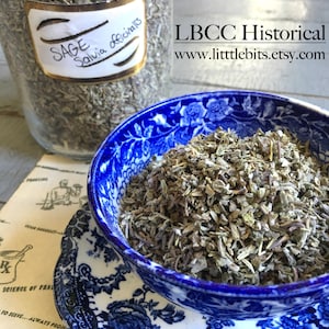 Puede incluir: Un cuenco azul y blanco estampado lleno de salvia seca, con un platillo a juego debajo. Un tarro de cristal de salvia est&aacute; en el fondo, con una etiqueta que dice "SAGE Salvia officinalis". Tambi&eacute;n se ve el texto "LBCC Historical" y una direcci&oacute;n web.