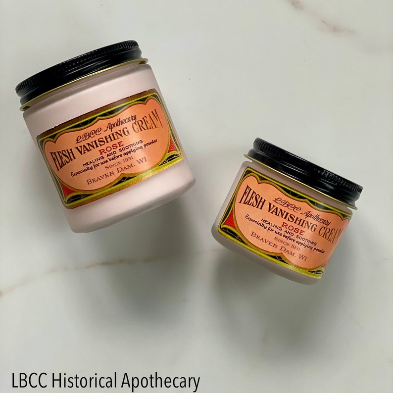 May include: Two jars of LBCC Apothecary Flesh Vanishing Cream Rose. The jars have a pink cream inside with a black lid and a label with text. The label is orange with black and red accents.