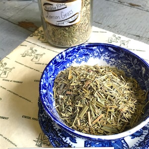 May include: A blue and white ceramic bowl filled with dried lemon grass. The bowl is sitting on a vintage book with the text "LBCC Historical Apothecary" printed on the cover.