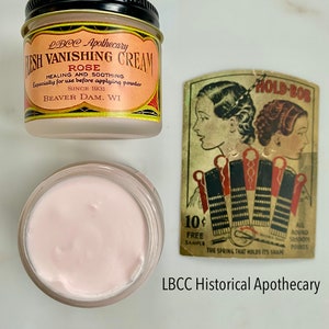 May include: A jar of LBCC Apothecary Flesh Vanishing Cream with a rose scent, and a vintage Hold-Bob hair accessory card. The cream is pink, and the jar has a black lid. The card features two women's profiles.