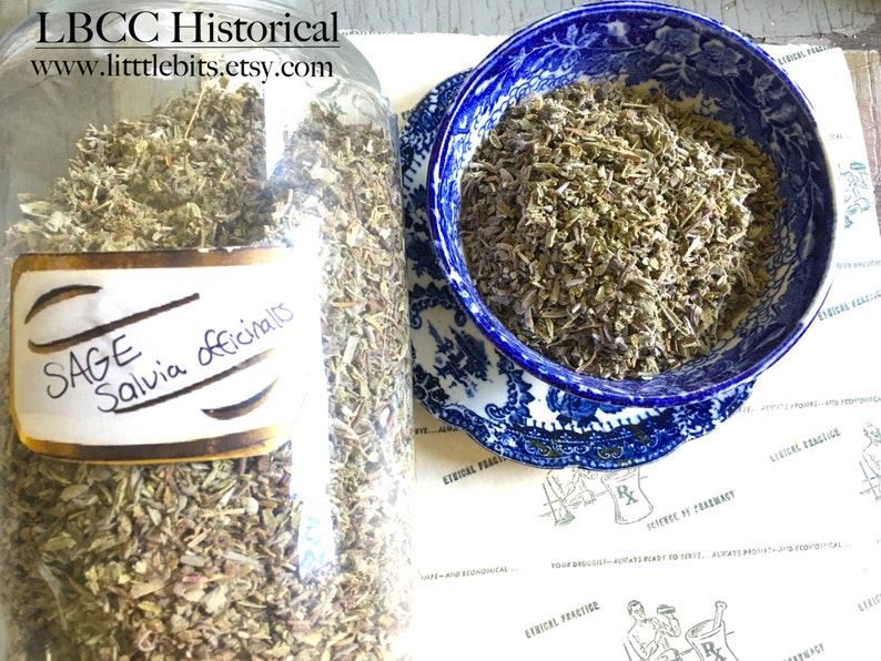 Puede incluir: Un gran tarro de vidrio lleno de salvia seca, etiquetado como "SAGE Salvia officinalis". Un cuenco azul y blanco con dibujos contiene m&aacute;s salvia. La imagen tambi&eacute;n muestra un plato estampado y el texto "LBCC Historical" y "www.littlebits.etsy.com."