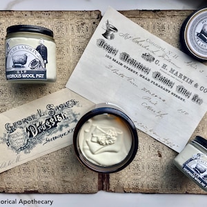 May include: An assortment of vintage apothecary items, including jars of "Pure Lanolin" and historical documents. The jars have black lids and labels with illustrations of a sheep. The documents feature handwritten text and ornate typography.