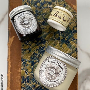 May include: Three glass jars with silver lids containing a white cream. The jars are labeled "Sultana Pomatum Apothecary 1772" and "Clears & Preserves The Complexion".