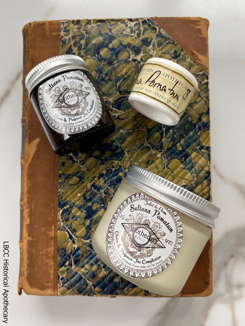 May include: Three glass jars with silver lids containing a white cream. The jars are labeled "Sultana Pomatum Apothecary 1772" and "Clears & Preserves The Complexion".