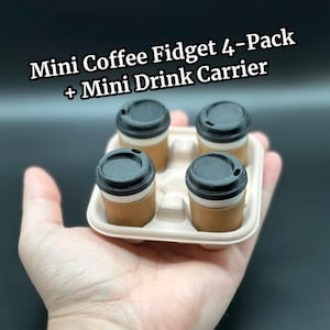 Może przedstawiać: Mini zestaw 4 fidgetów do kawy z mini uchwytem na napoje. Zestaw zawiera cztery małe filiżanki do kawy z czarnymi pokrywkami, w beżowym uchwycie na napoje. U góry widnieje napis "Mini Coffee Fidget 4-Pack + Mini Drink Carrier".
