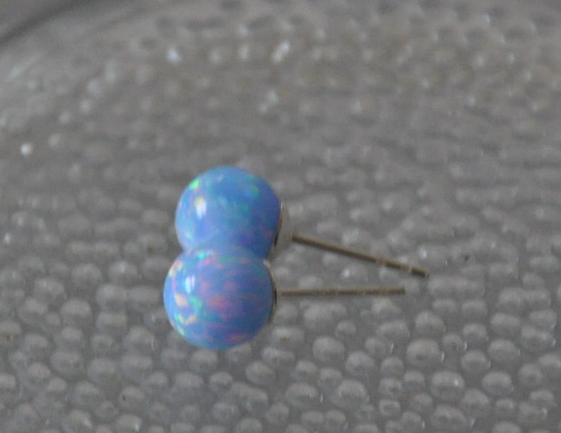 May include: A pair of blue opal stud earrings with silver posts.