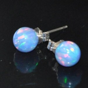 May include: A pair of silver stud earrings with light blue opal stones. The opals have a shimmering iridescent effect.