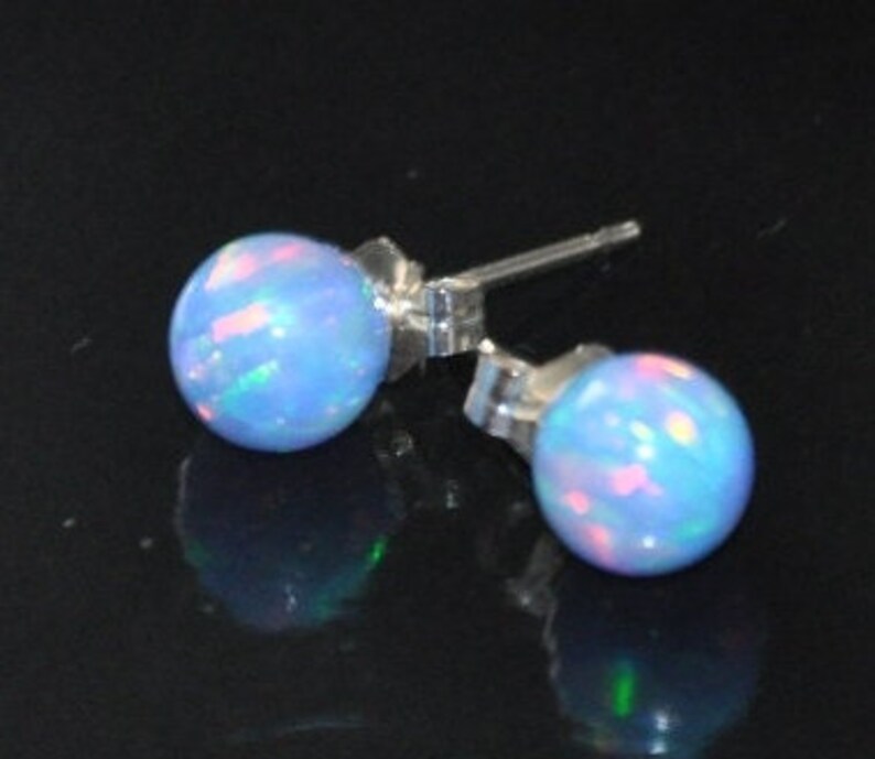 May include: A pair of silver stud earrings with light blue opal stones. The opals have a shimmering iridescent effect.