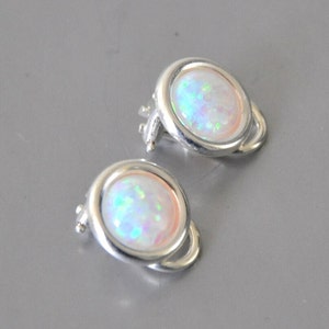 May include: A pair of silver clip-on earrings with white opal stones.