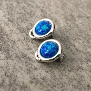 May include: A pair of silver clip-on earrings with blue opal stones.