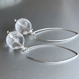May include: A pair of silver earrings with clear faceted crystal ball drops. The earrings have a simple, elegant design.