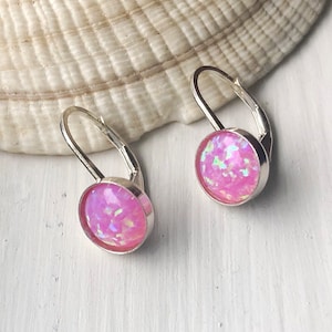 Peut inclure: Une paire de boucles d'oreilles créoles en argent avec des pierres d'opale rose. Les boucles d'oreilles ont un design simple et sont parfaites pour tous les jours.
