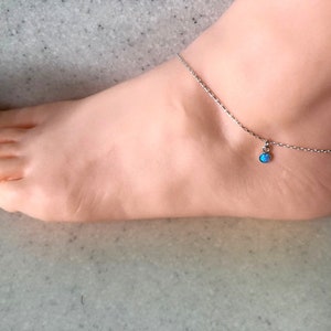 May include: A silver anklet with a small blue opal charm.