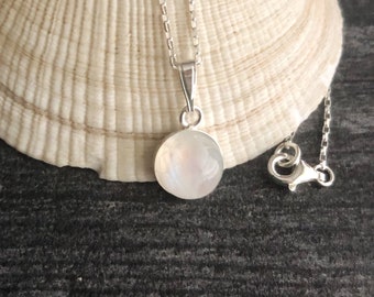 May include: A silver chain necklace with a round, iridescent moonstone pendant.