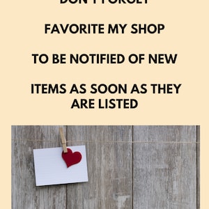 May include: A white card with a red heart attached to it is hanging on a wooden surface with a string and clothes pegs. The card has the text "DON'T FORGET FAVORITE MY SHOP TO BE NOTIFIED OF NEW ITEMS AS SOON AS THEY ARE LISTED".